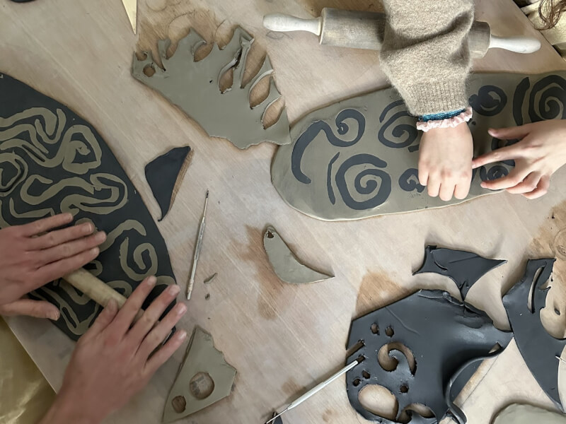 Two people sit at a table, creating nerikomi clay ready to make into pots